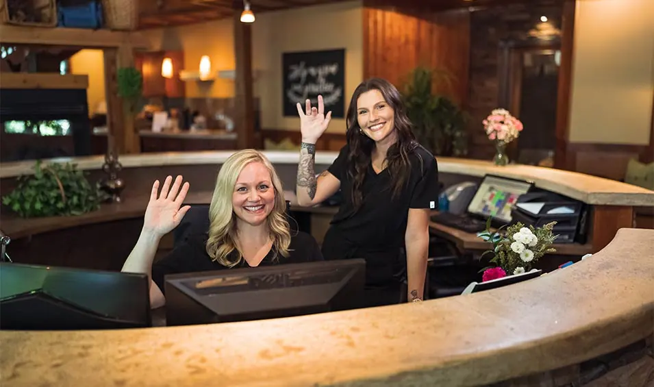 front desk staff smiling and waving at Dental Bliss
